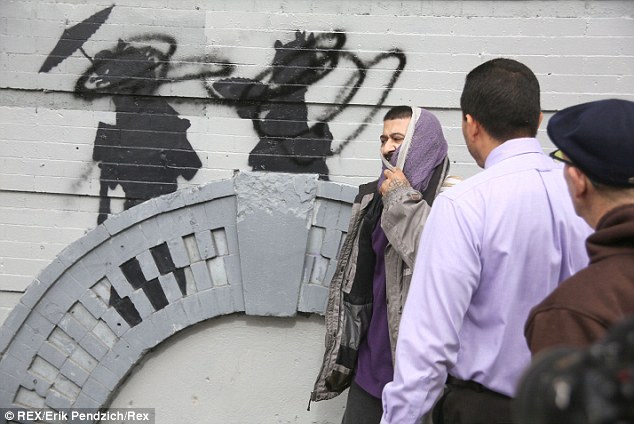 A building superintendent confronts the tagger after he painted black scribbles over Banksy's work