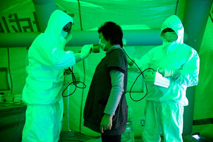 Японские медики исследуют организм женщины на наличие возможной радиации при помощи аппарата Гейгера. © Asahi Shimbun/Reuters