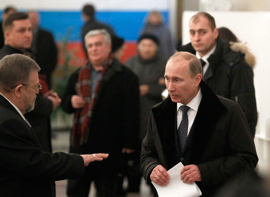 Владимир Путин держит бюллетень на одном из избирательных участков в Москве. © Grigory Dukor/Reuters
