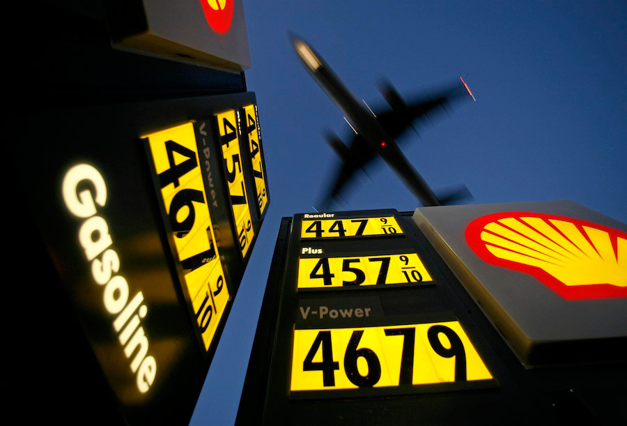 Заправочная вывеска с ценами на бензин, над которой пролетает заходящий на посадку самолет, Калифорния. © Mike Blake/Reuters