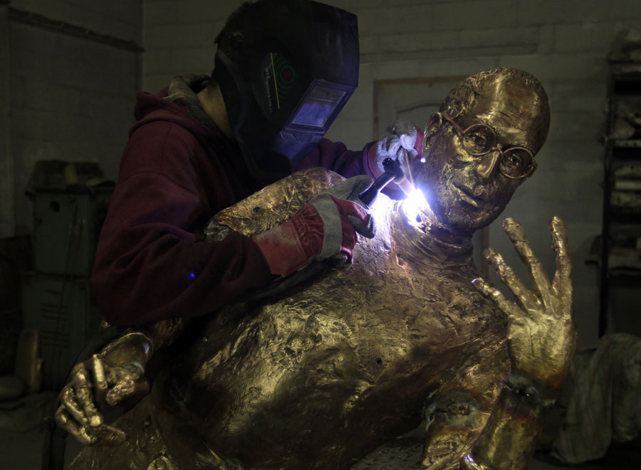 Ассистент скульптора прикрепляет голову Джобса к телу. © LASZLO BALOGH/Reuters