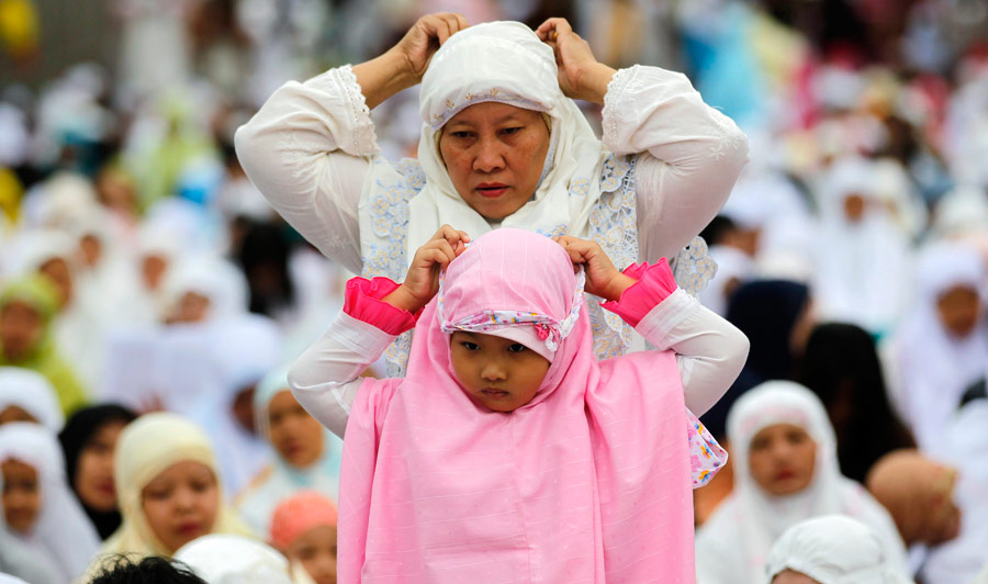 Мусульманка с дочерью готовятся принять участие в праздничной молитве в день Ид аль-Адха в Джакарте, Индонезия. © Supri/Reuters