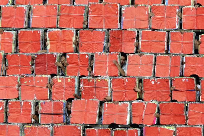 Корейцы держат в руках картон, создавая тем самым фон для массовых гимнастических выступлений в Пхеньяне.