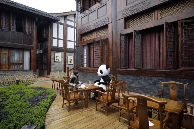 Сотрудник отеля в костюме панды разговаривает с клиентом на тему открытия заведения у горы Эмеи.