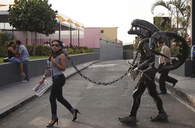 Женщина ведет на поводке человека в костюме чужого во время празднования 478-й годовщины испанского основания в городе Лиме, Перу.