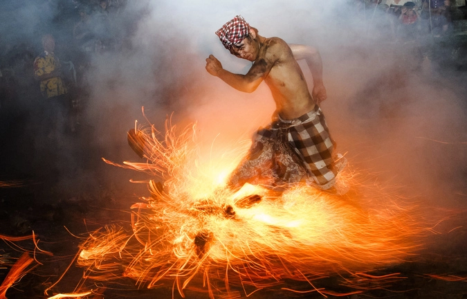 Балиец что-то делает с огнем, совершая ритуал "Perang Api", во время дня Nyepi в Индонезии.