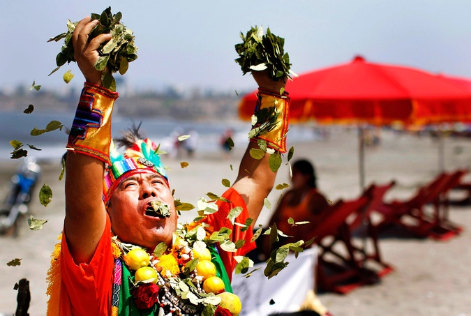 Шаман рассыпает листья коки на пляже Агуы Дулси в Лиме, Перу.