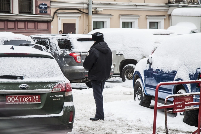 Человек в форме полицейского иностранного государства, который вместо охраны здания консульства по видимому работает парковщиком не разрешая гражданам РФ парковаться на территории РФ. 