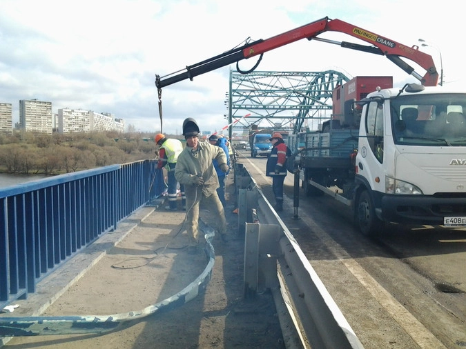 Сварщик Сергей Пискун режет сваркой покореженные детали ограждения моста