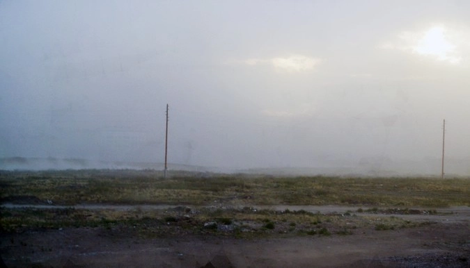 С того же ракурса, что и прежнее фото, но за стеной песка уже не видно ни вышек, ни строений. Такая она, песчаная буря.