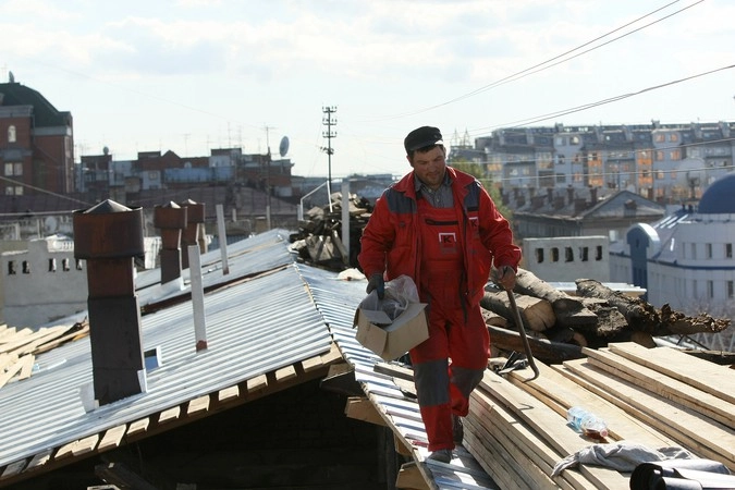 Рабочие-кровельщики проводят капитальный ремонт крыши.