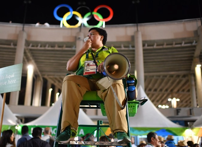 Волонтер у стадиона "Таракана" перед началом церемонии открытия XXXI летних Олимпийских игр.