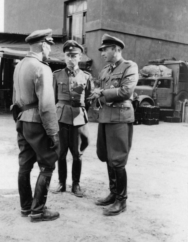 34-летний Гельмут Бартельмес, командир зенитного дивизиона, беседует с Фегеляйном и неизвестным офицером. Интересно, что из своих наград он носил только наивысший орден &mdash; Железный крест 1-го класса.