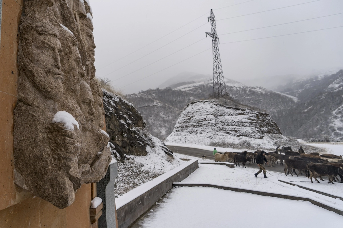 Карабахские армяне - жители покинутой деревни в Лачинском районе гонят стадо по шоссе по направлению Армении, мимо армянского монумента.