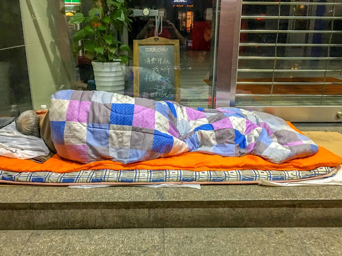 Бездомный спит на улице в Шанхае