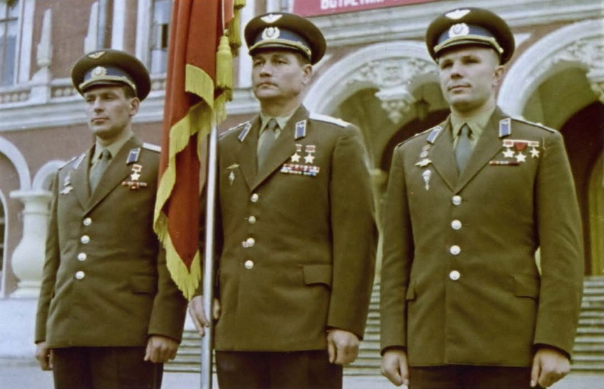 Лётчики-космонавты Ю.А. Гагарин (справа) и Г.С. Титов (слева) у знамени Военно-воздушной инженерной академии имени Н.Е. Жуковского; по центру стоит боевой лётчик, инженер-полковник, кандидат технических наук Г.Ф. Сивков. Фото из альбома «Гагарин — известный и неизвестный» (2009)