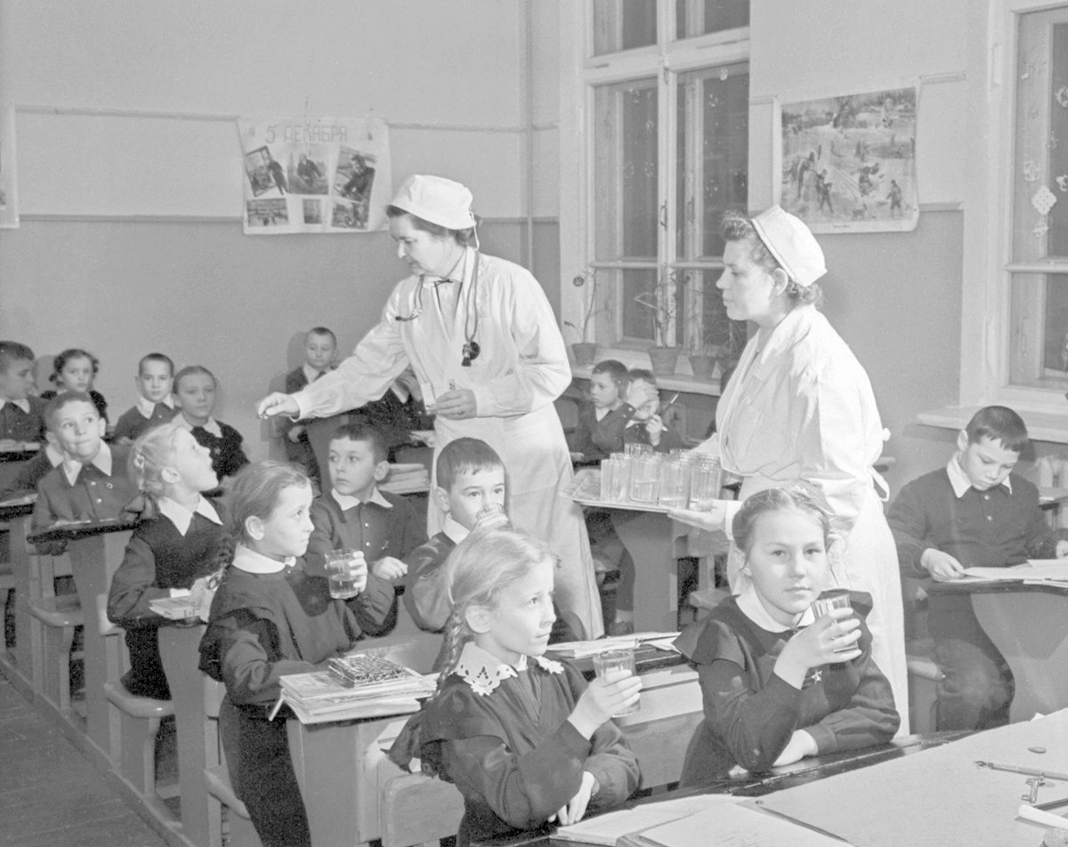 Врач школы и медсестра раздают школьникам драже с вакциной против полиомиелита. 18 января 1960 года.