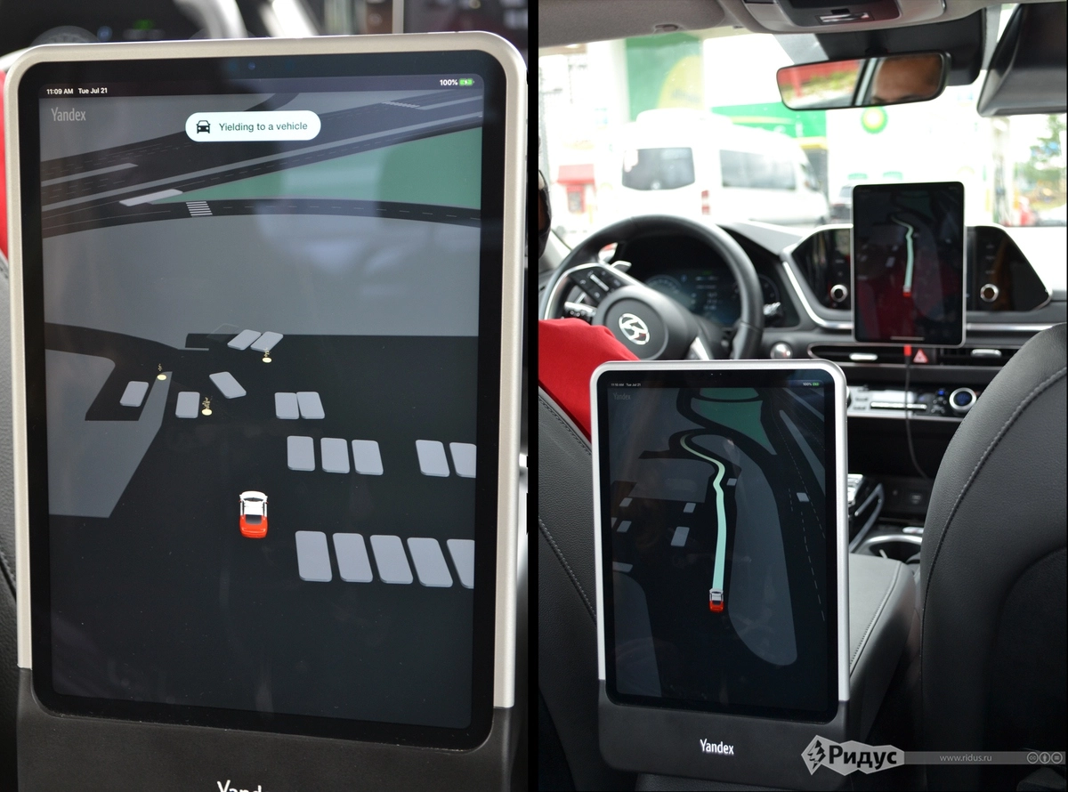 На планшете показано, как видит дорогу автопилот: серые прямоугольники - авто, желтые пятна - люди. 