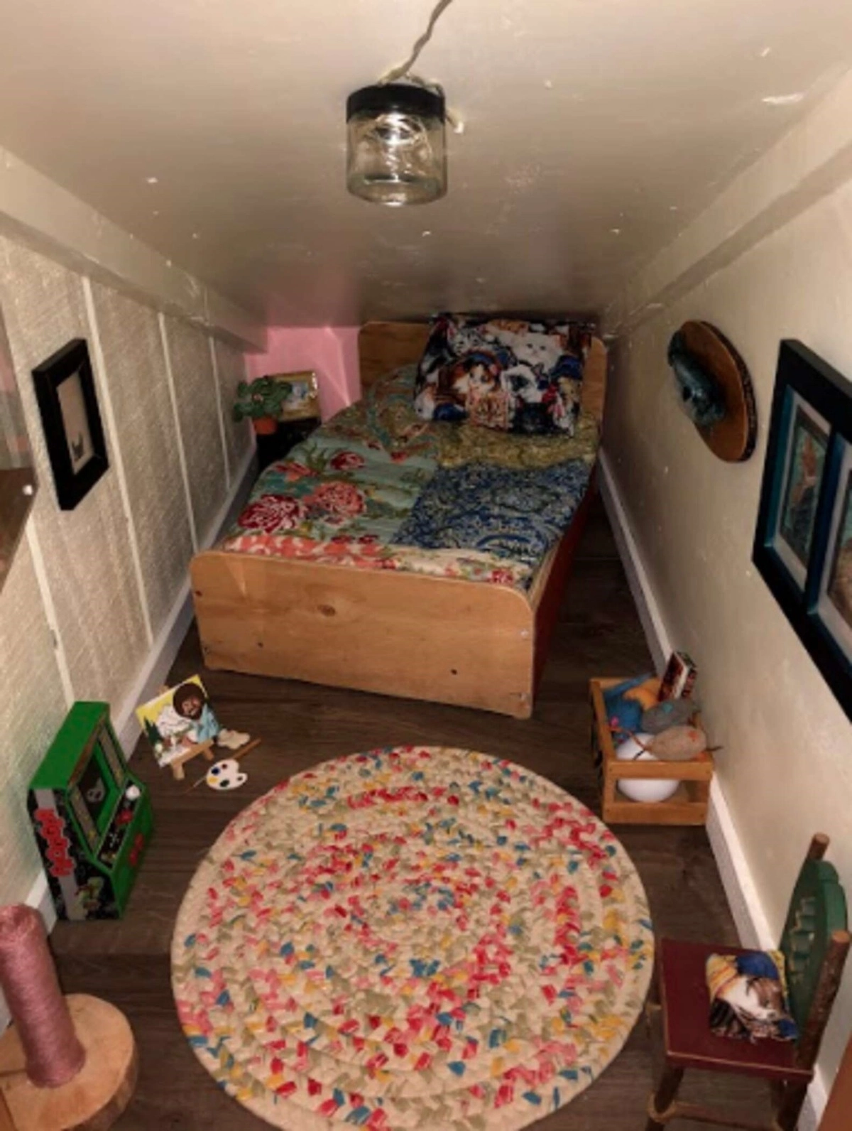 В комнатке есть маленькая кровать, картины и даже телевизор