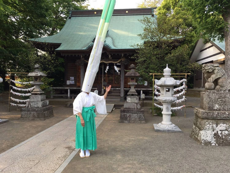 Главный священник храма 49-летняя Мивако Кодзима проводит церемонию в бело-зеленом костюме с причудливым двухметровым головным убором в виде зеленого лука