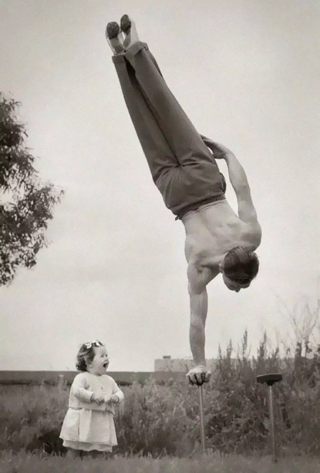 Австралиец демонстрирует свою физическую форму маленькой дочке, 1940-е годы. 
