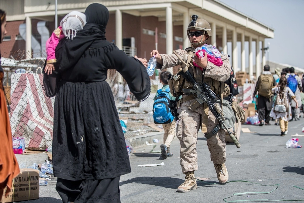 Американский морской пехотинец делится водой с афганской женщиной