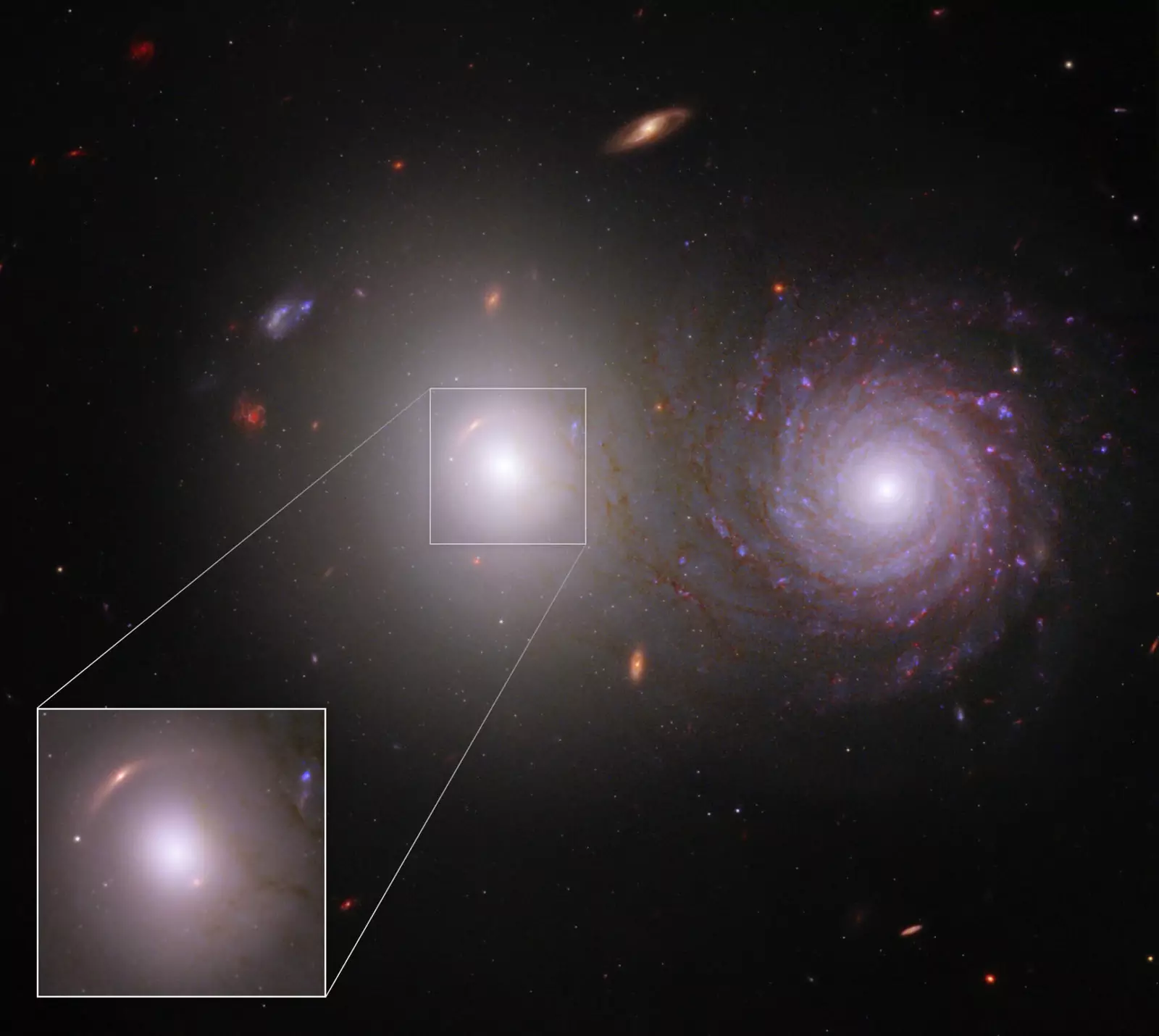 За эллиптической галактикой видно уникальное зрелище - отблески другой, более далёкой галактики.